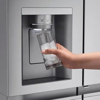Une main remplit un verre de glaçons à partir du distributeur intégré d’un réfrigérateur congélateur LG. De la glace sort du distributeur situé à l’avant de la porte du réfrigérateur.