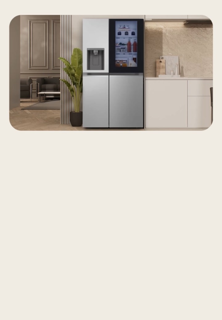 Réfrigérateur congélateur LG américain argenté avec InstaView et distributeur d’eau placés au centre. Une grande plante est à gauche et une cuisine moderne est visible à droite.