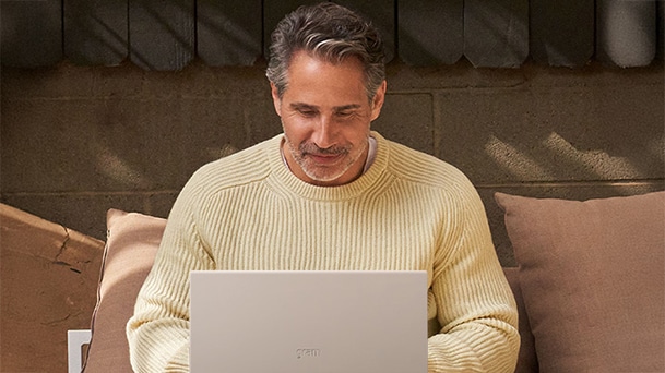 L’image montre un homme en pull jaune assis sur un canapé, travaillant sur un ordinateur portable avec le texte « Les plus grandes entreprises ont déjà déployé de nouveaux PC Windows 11 Pro ».