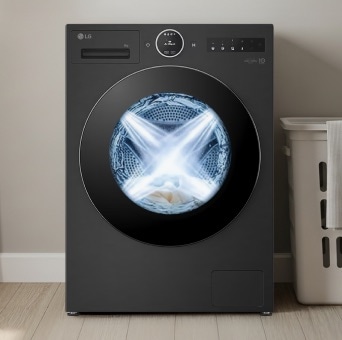 LG Black front loading washer in a modern multipurpose room. A laundry basket sits next to the machine, and the interior of the dryer looks brightly burning.