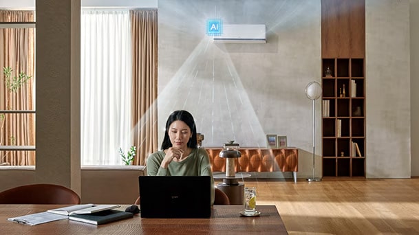 AC LG DUALCOOL AI mendinginkan seorang wanita yang bekerja di meja dengan laptop di ruang keluarga.
