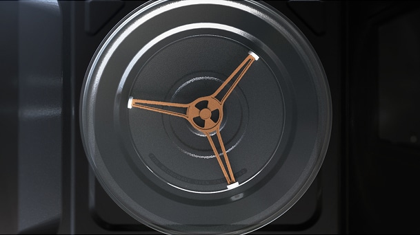 Overhead view shows a round glass turntable with three rings on a dark microwave base.