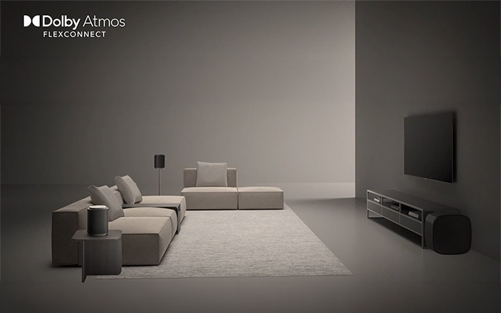 LG TV Sound Suite with DAFC (Dolby Atmos FlexConnect) shows a wide room where the TV and wireless speakers are freely positioned, conveying immersive Dolby Atmos audio optimized for flexible speaker placement.