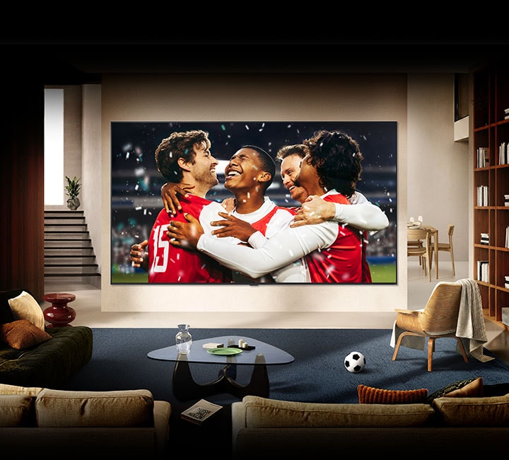LG TV wall-mounted in a bright living room shows a stadium sports celebration with vivid colors and refined picture quality on a wide screen.