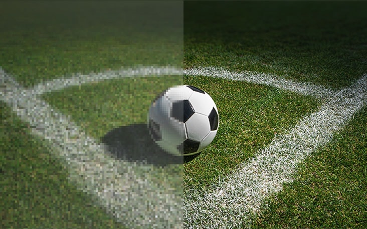 LG TV for sports viewing with AI upscaling shows a split-screen close-up of a soccer ball, where the left side appears blurred and the right side sharper with clearer turf texture, illustrating improved clarity for sports viewing.