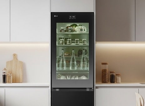 Frigorifero alto LG con porta in vetro trasparente in una cucina minimalista. L’interno è illuminato da una luce verde, che mostra chiaramente gli alimenti freschi e le bevande conservate.