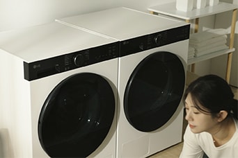 Paire de grandes machines à laver LG à chargement par l’avant avec une femme à proximité, mettant en valeur une capacité spacieuse pour de grandes charges de linge.