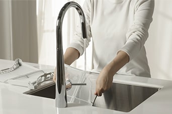 Personne rinçant un filtre à peluches à l’eau courante, démontrant un nettoyage et un entretien faciles à double filtre.
