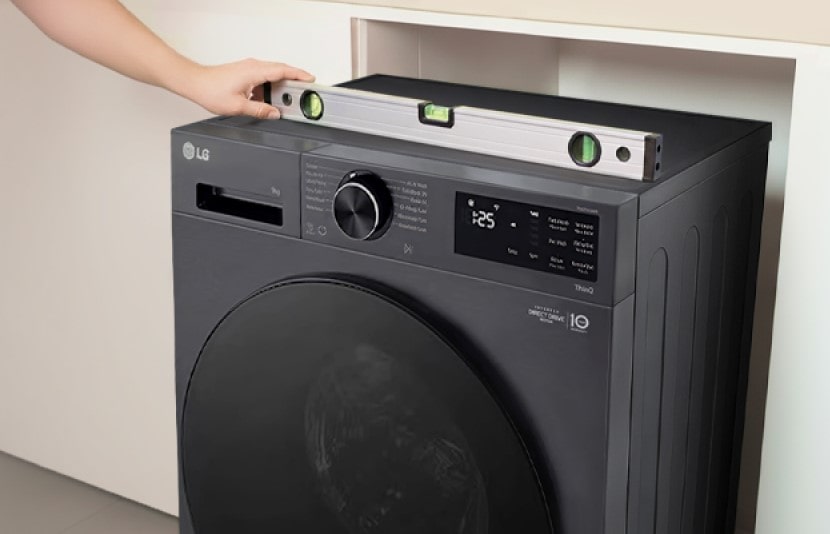 Lavadora LG alineada con un nivel de burbuja durante su instalación dentro de un gabinete empotrado