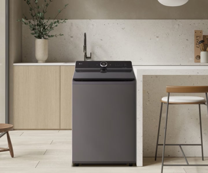 Lavadora de carga superior LG colocada en un espacio moderno estilo cocina con un interior minimalista y taburetes de bar