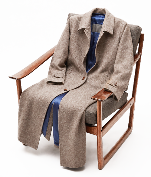 A beige coat and blue collared shirt neatly draped over a folding chair.
