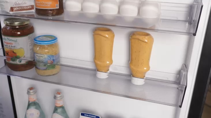 LG Fridge Freezer door with mini baskets holding sauces, jars, and beverages.