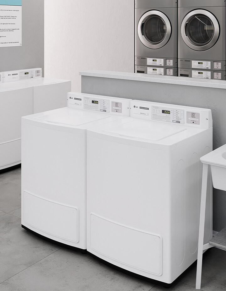 Commercial top-load washers installed in a clean and organized multi-housing laundry space