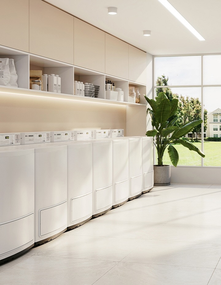 Bright shared laundry room with commercial washers, dryers, and ample open space	