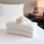 Freshly folded white towels placed on a hotel bed, symbolizing cleanliness and guest comfort	
