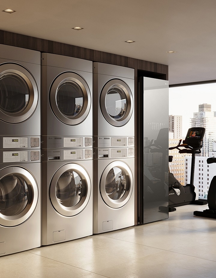 On-premises laundry room next to a fitness area with stacked washers and dryers overlooking the city	