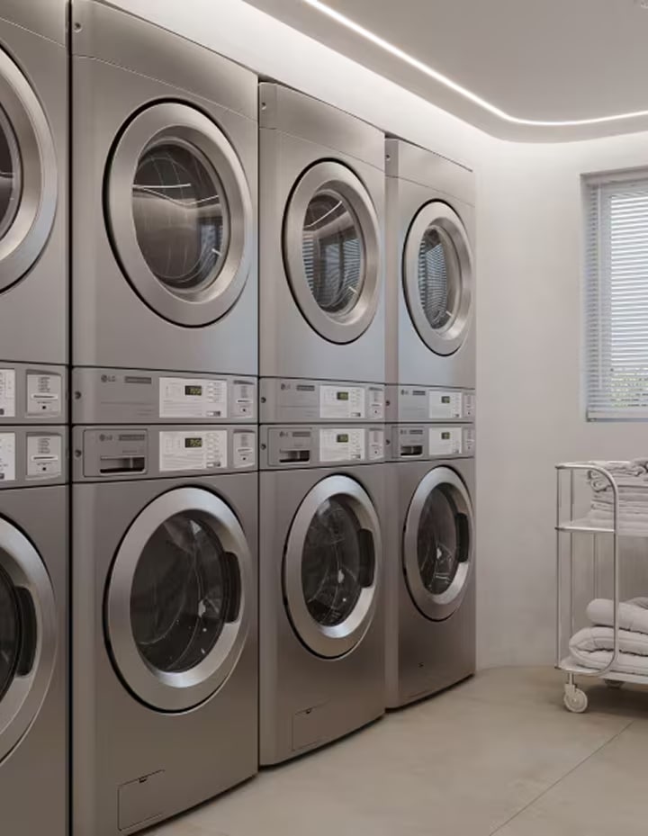 Bright on-premises laundry room with stacked commercial washers and neatly arranged towel carts	