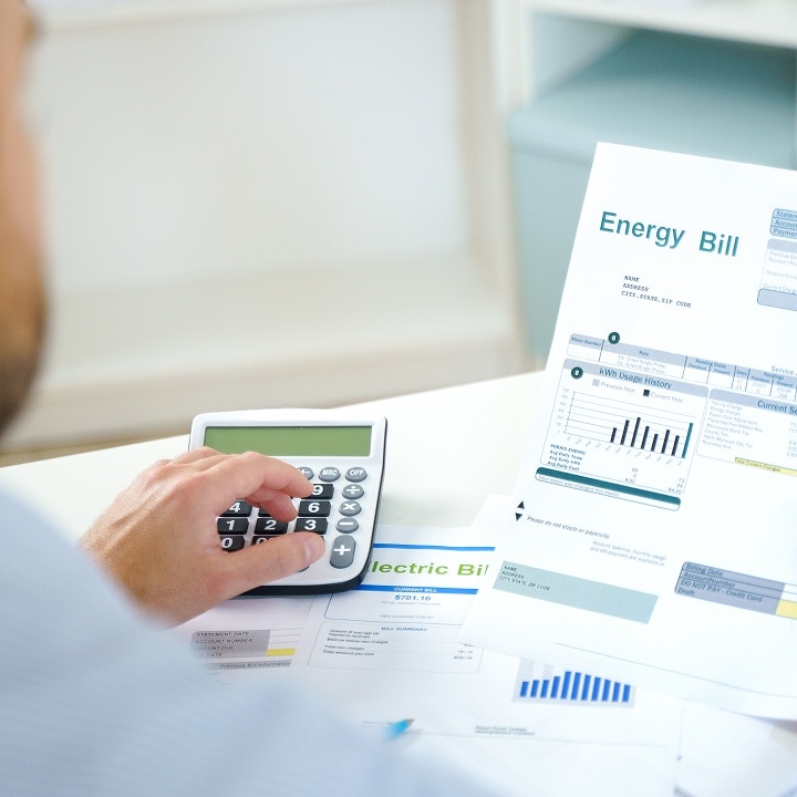 Person calculating costs while reviewing an energy bill, illustrating how saving energy bills is possible with LG's energy efficient refrigerator	