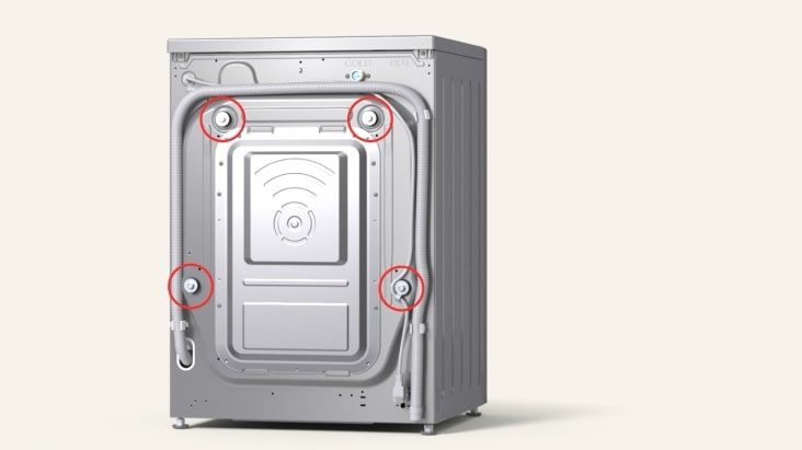 Zadní panel předem plněné pračky LG s přepravními šrouby označenými k odstranění před instalací.