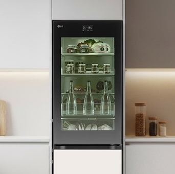 LG tall fridge with a see through glass door in a minimalist kitchen. The interior is lit with green lighting, clearly showing stored fresh groceries and beverages.