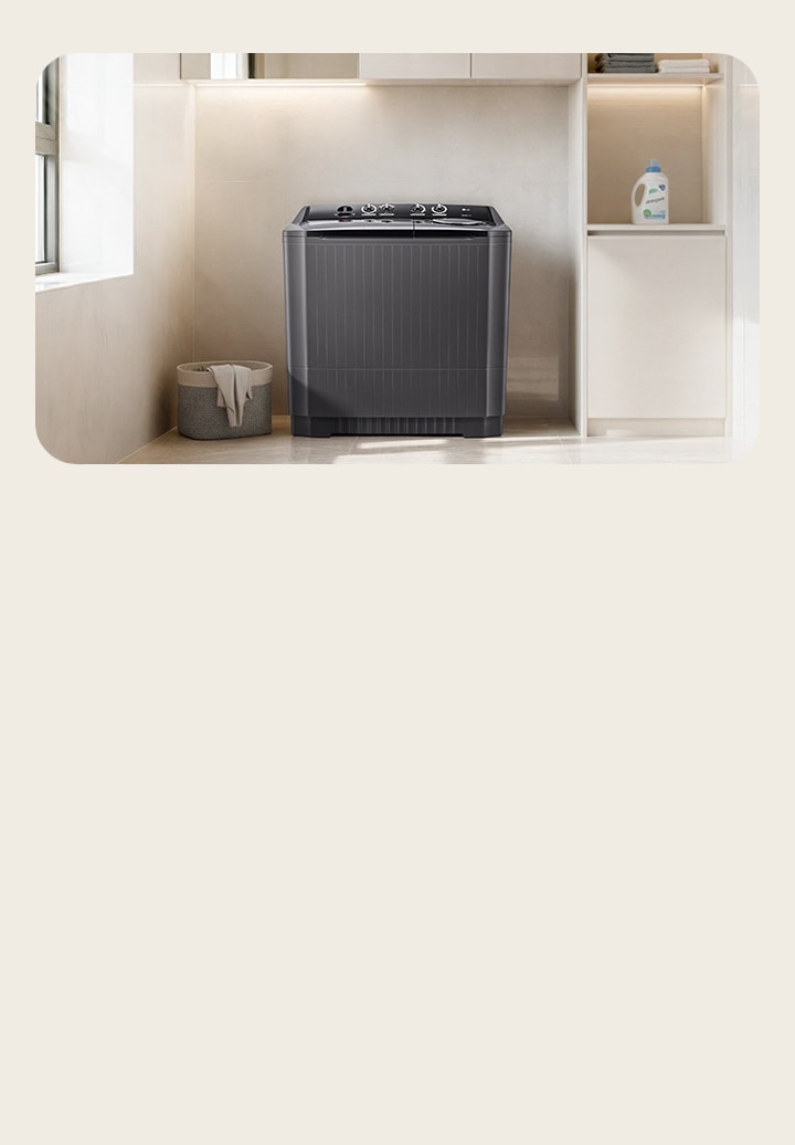 There is a twin washing machine in the center of a modern multipurpose room with a wide light brown interior. The light comes from the left window, and there is detergent on the right shelf.