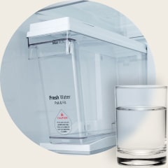 لقطة مقرّبة لصانع الثلج LG Non-Plumbing Ice Maker لعام 2007 المزود بخزان مياه Pull & Fill، مع كوب ماء موضوع في المقدمة.