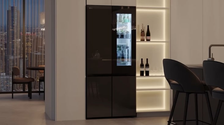 LG InstaView refrigerator in modern home bar area with warm lighting and city view, blending with elegant interior design.	