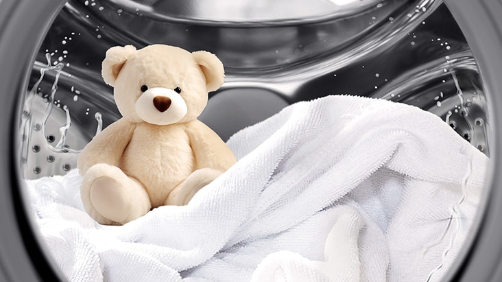 LG-tvättmaskin med en nallebjörn och vit handduk inuti