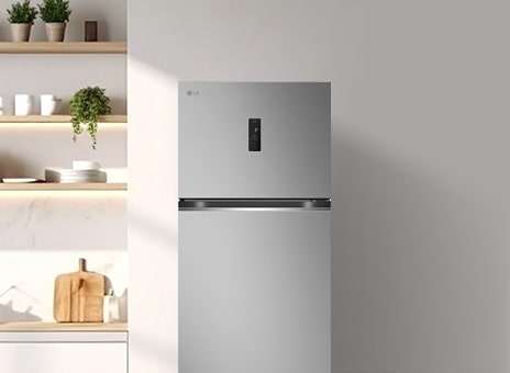 Silver top-freezer refrigerator placed in a modern kitchen with open shelving and minimalist decor.