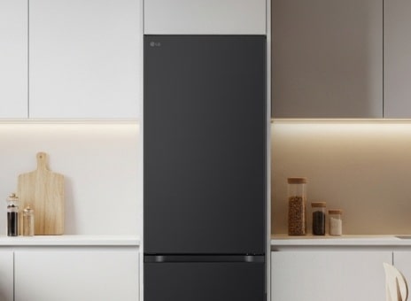 Black bottom-freezer refrigerator built into a modern kitchen cabinet.