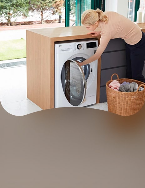 Woman loading laundry into built-in LG washing machine in modern laundry area