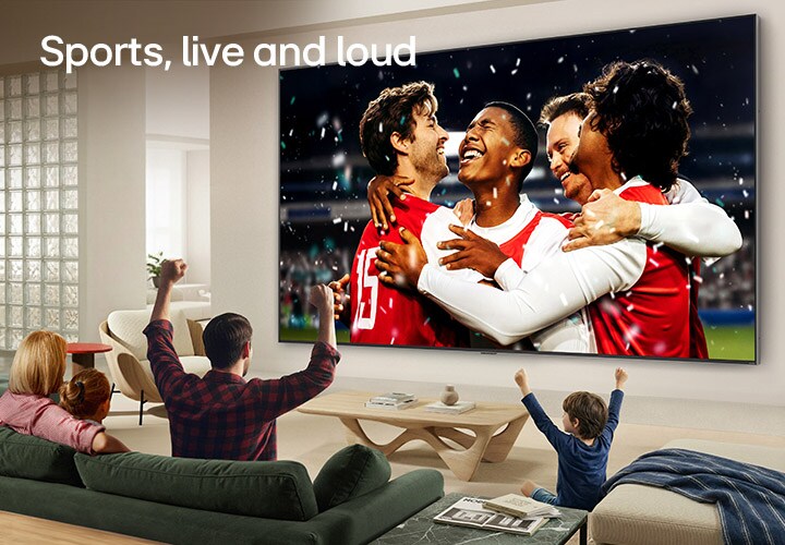 LG Ultra Büyük TV, aydınlık bir oturma odasında duvara monte edilmiş. Geniş ekranda canlı renkler ve gelişmiş görüntü kalitesiyle bir stadyum spor kutlaması gösterilirken kanepelerde oturan bir aile hep birlikte tezahürat yapıyor.