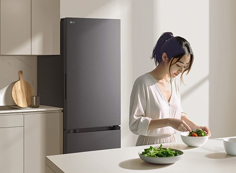 現代風格廚房中的白色 LG 雙門冰箱。一位女士在桌邊吃著早餐。