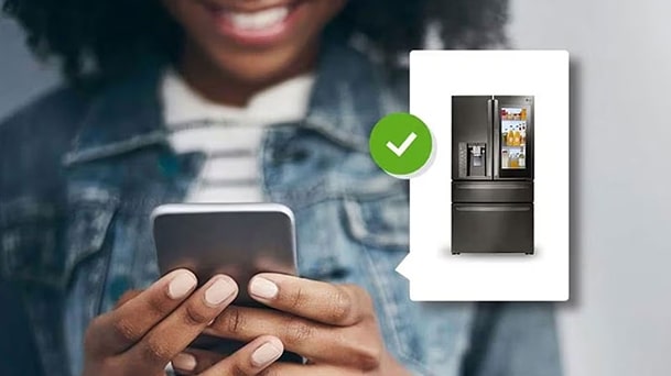 Person using smartphone to remotely monitor and control LG smart refrigerator