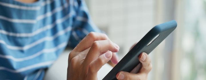 Person using a smartphone to access and control smart fridge functions remotely through the LG ThinQ app	