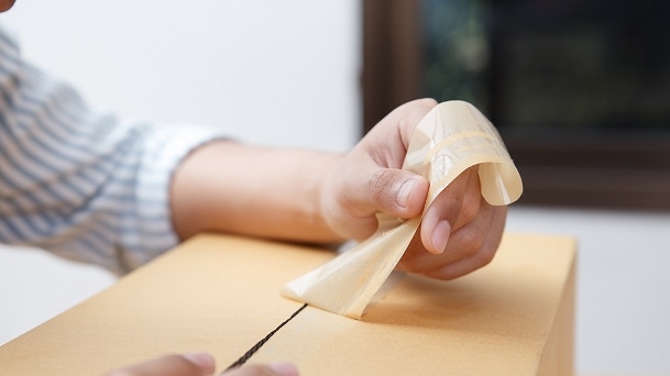 Person unsealing a cardboard box during LG refrigerator unboxing process at home	