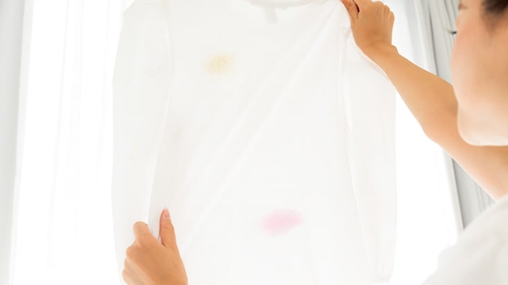 Person holding up a white shirt with visible stains