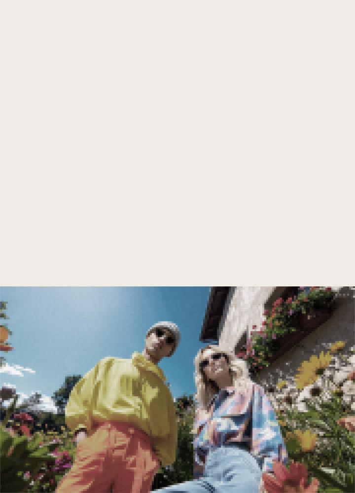 LG QNED evo AI QNED82 Mini LED with AI Picture Pro shows a low-angle outdoor lifestyle scene with two people among vivid flowers, as AI recognizes and upscales each frame to 4K for clearer texture and detail.