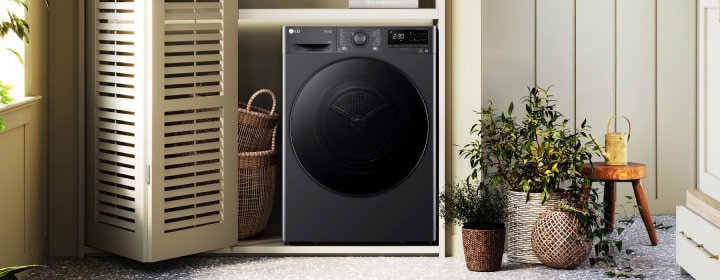 Máy sấy cửa trước LG được lắp đặt trong không gian giặt ủi hiện đại bên cạnh tủ gỗ, điểm xuyết cây xanh và tràn ngập ánh sáng tự nhiên
