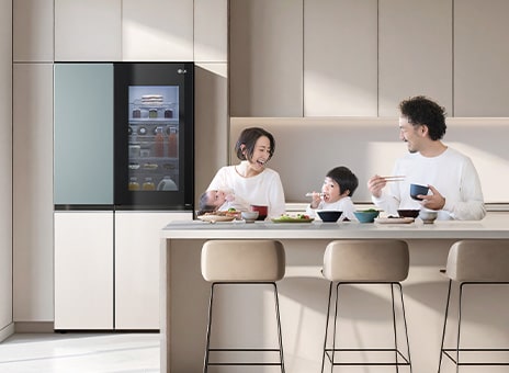 Tủ lạnh InstaView của LG trong một căn bếp sáng sủa. Bên trong cánh cửa là hộp nước cam ép. Một người đàn ông và một người phụ nữ đang nhìn mẹ của họ, ở giữa có một đứa trẻ mặc áo sơ mi trắng.