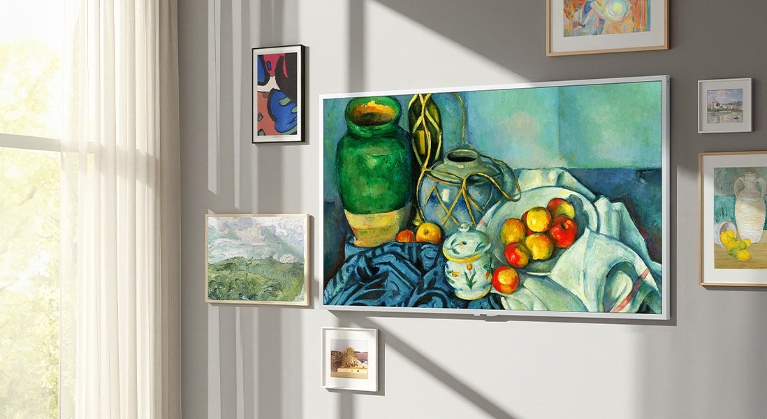 LG Gallery TV AI with frame LX7 ART TV sở hữu Gallery-like Screen được treo tường, hiển thị một bức tranh tĩnh vật. TV được đặt gần cửa sổ với các tác phẩm nghệ thuật đóng khung khác và dù có ánh sáng mặt trời chiếu vào, màn hình vẫn không xuất hiện hiện tượng phản chiếu rõ rệt, tạo cảm giác như một tác phẩm nghệ thuật thực thụ.