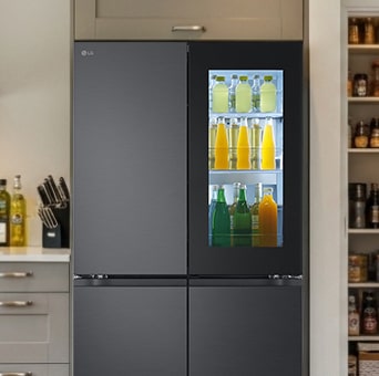 LG matte black Multi-Door fridge freezer with InstaView Door-in-Door open, showing fresh food storage. To the right, pantry shelves are filled with groceries.