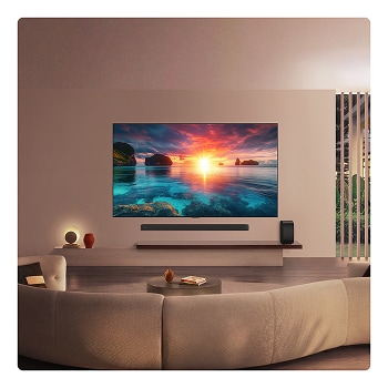 LG OLED evo AI G6 displays a vivid ocean sunset scene, with a soundbar and speaker positioned below the screen, enhancing a calm and atmospheric living space.