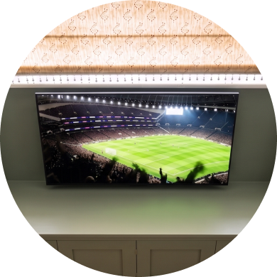 Ein ultrabreiter, gebogener TV zeigt ein Fußballstadion aus der Vogelperspektive.