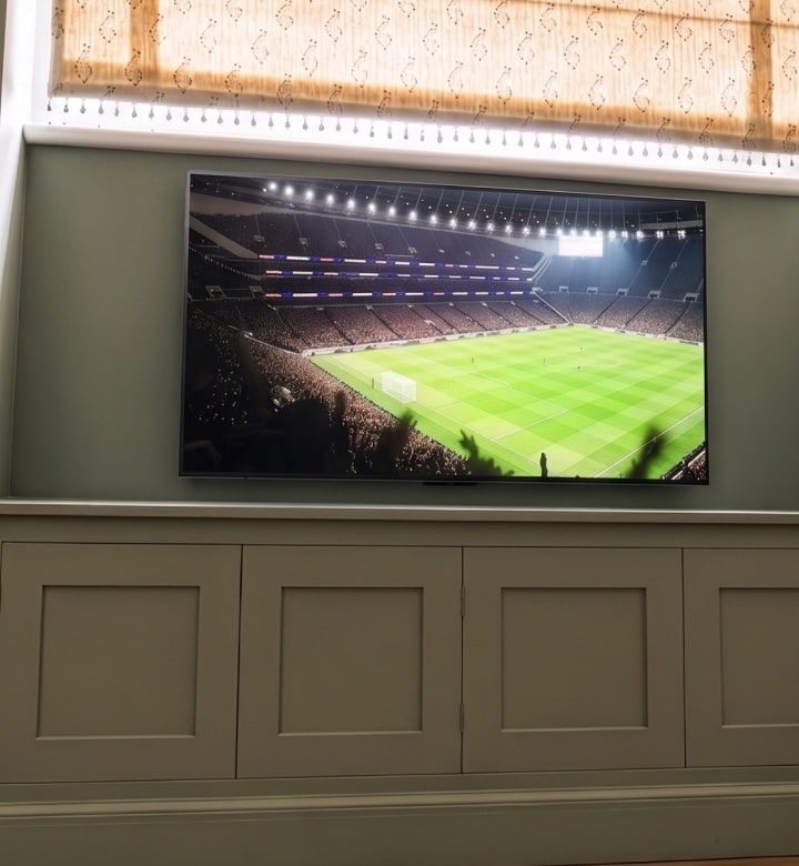 Ein gebogener TV zeigt ein Live-Fußballspiel in einer Wohnumgebung.