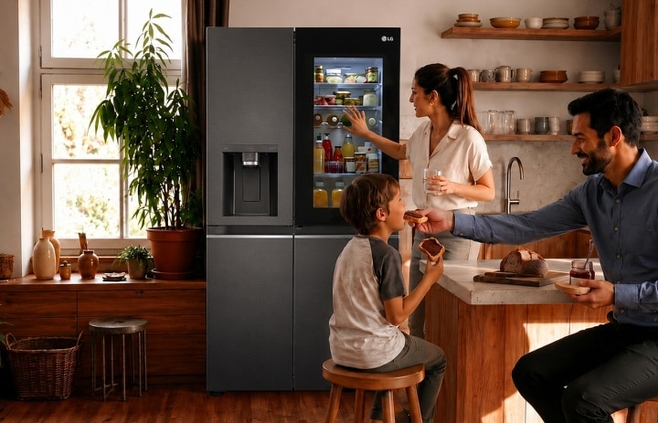 Eine Familie in einer warmen, modernen Küche, eine Frau greift in einen schwarzen LG-Kühlschrank, während ein Mann ein kleines Kind an der Kücheninsel füttert.