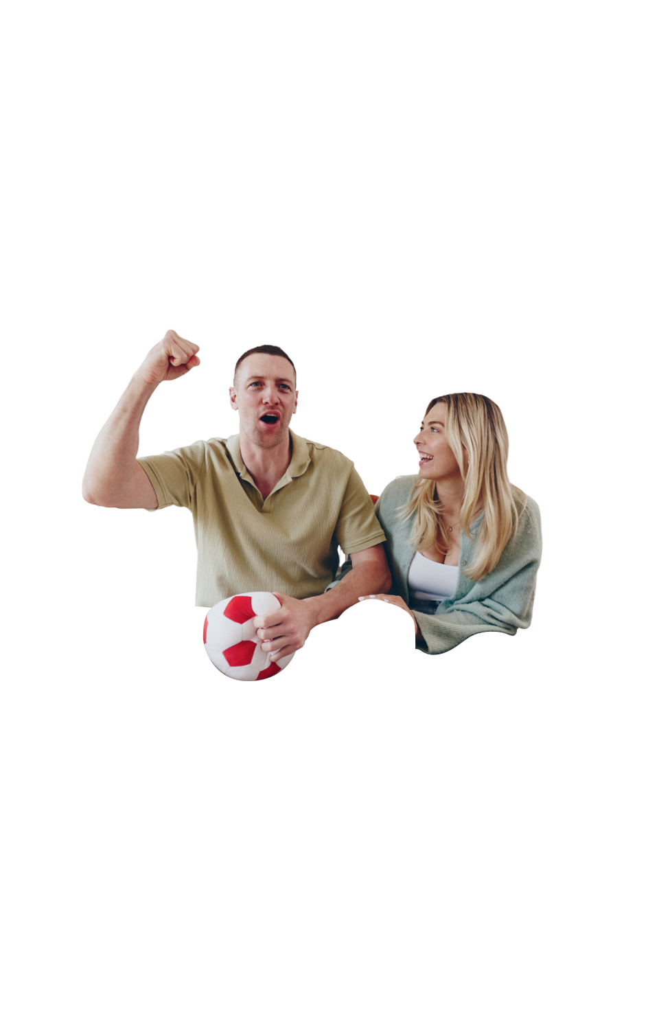 Ein Mann sitzt auf einem Sofa, jubelt und hält ein Fußball-Plüschtier, während eine Frau ihn anlacht.