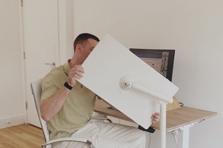 Ein Mann, der auf einem Stuhl sitzt und einen StanbyME 2 Smart Screen auf einen 45-Grad-Winkel dreht.