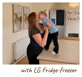 Eine Mutter hält ihr Baby in einer modernen Küche und steht neben einem offenen Kühlschrank. [mit LG-Kühl-Gefrierkombination]