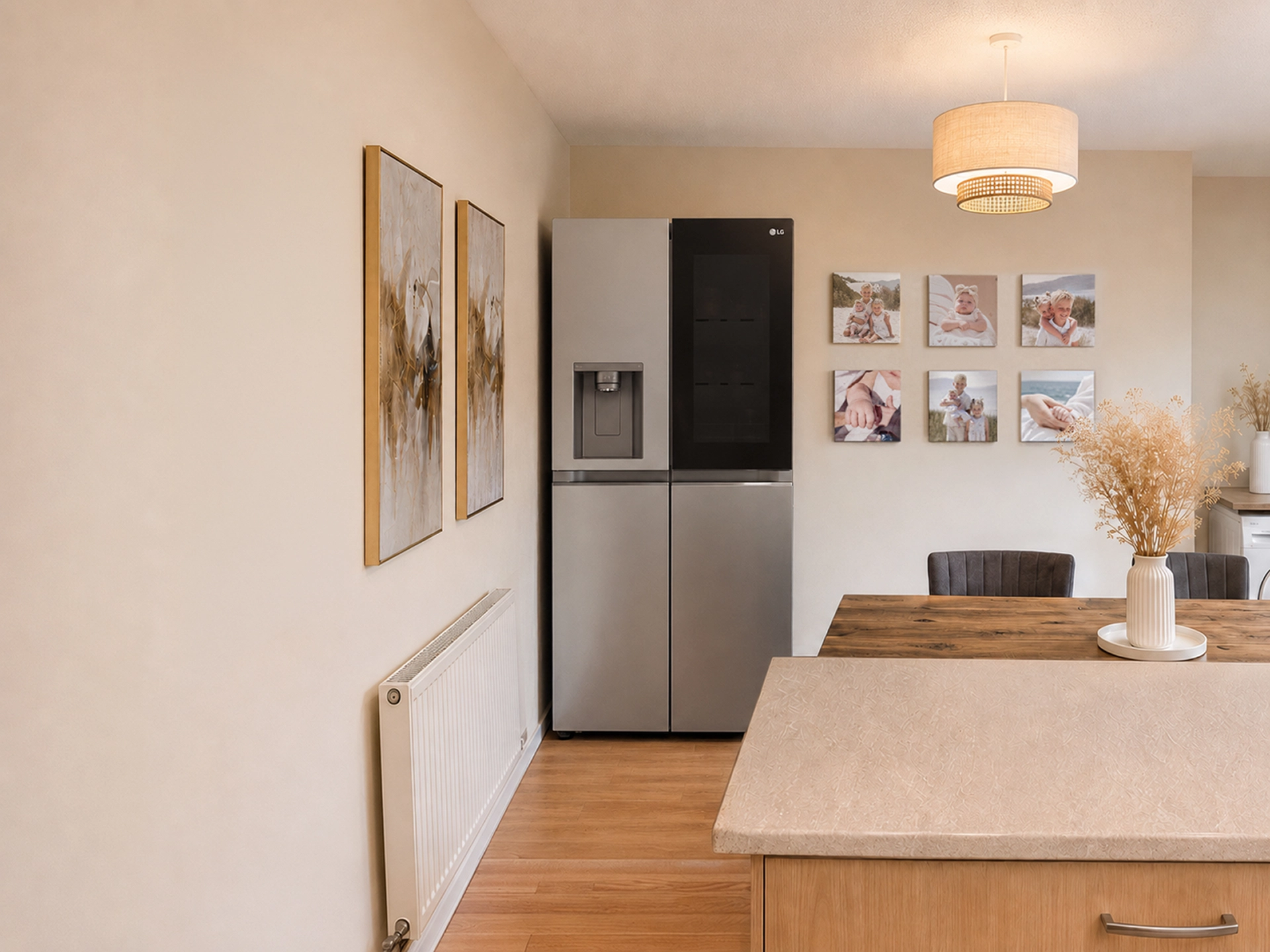 Ein LG-Edelstahl-Multi-Door-Kühl-Gefrierschrank steht in einem warmen, modernen Esszimmer neben einem Holztisch und einer Wanddekoration.